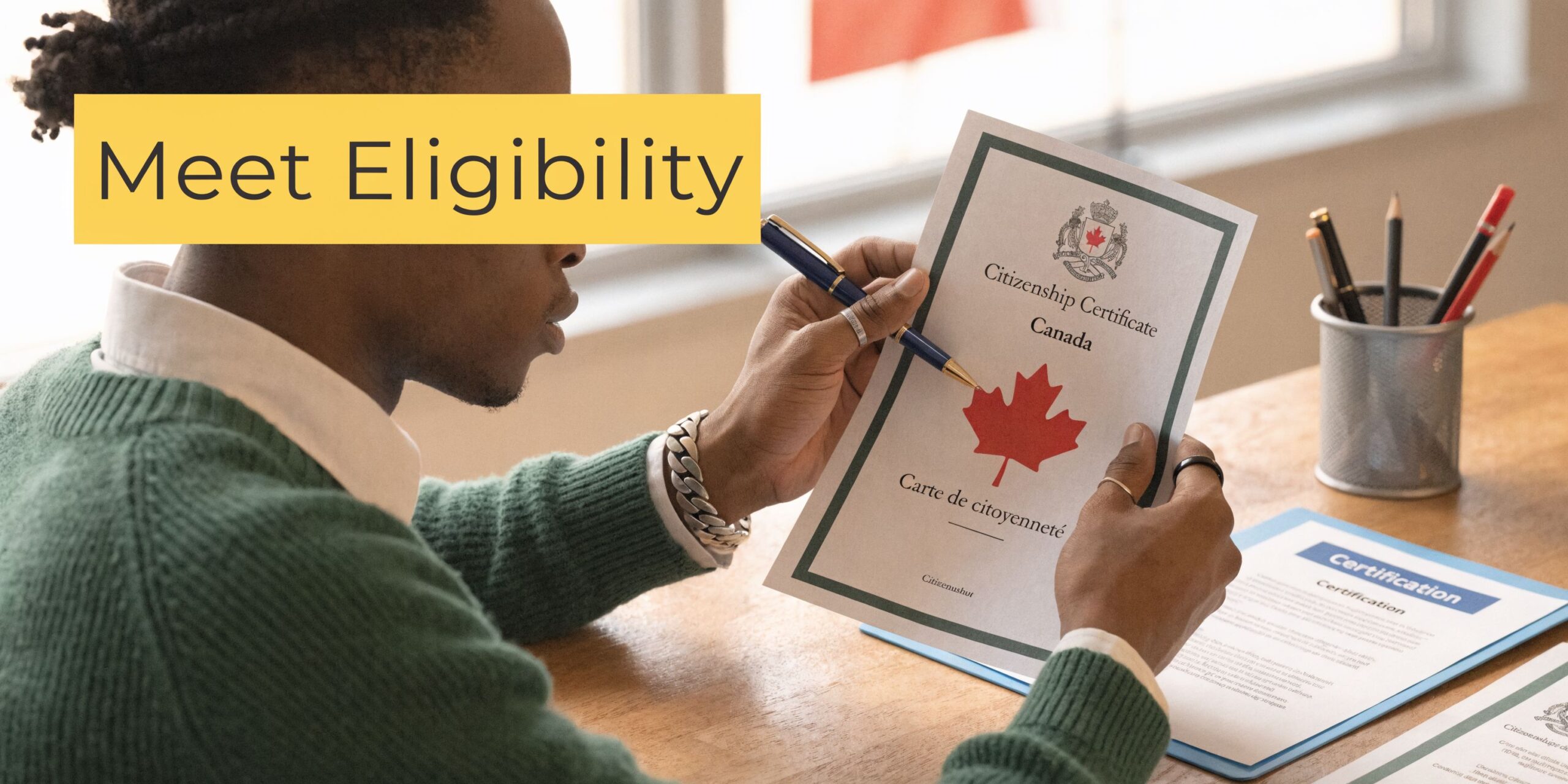 A person reviewing their official Canadian citizenship certificate while sitting at a desk with writing supplies.