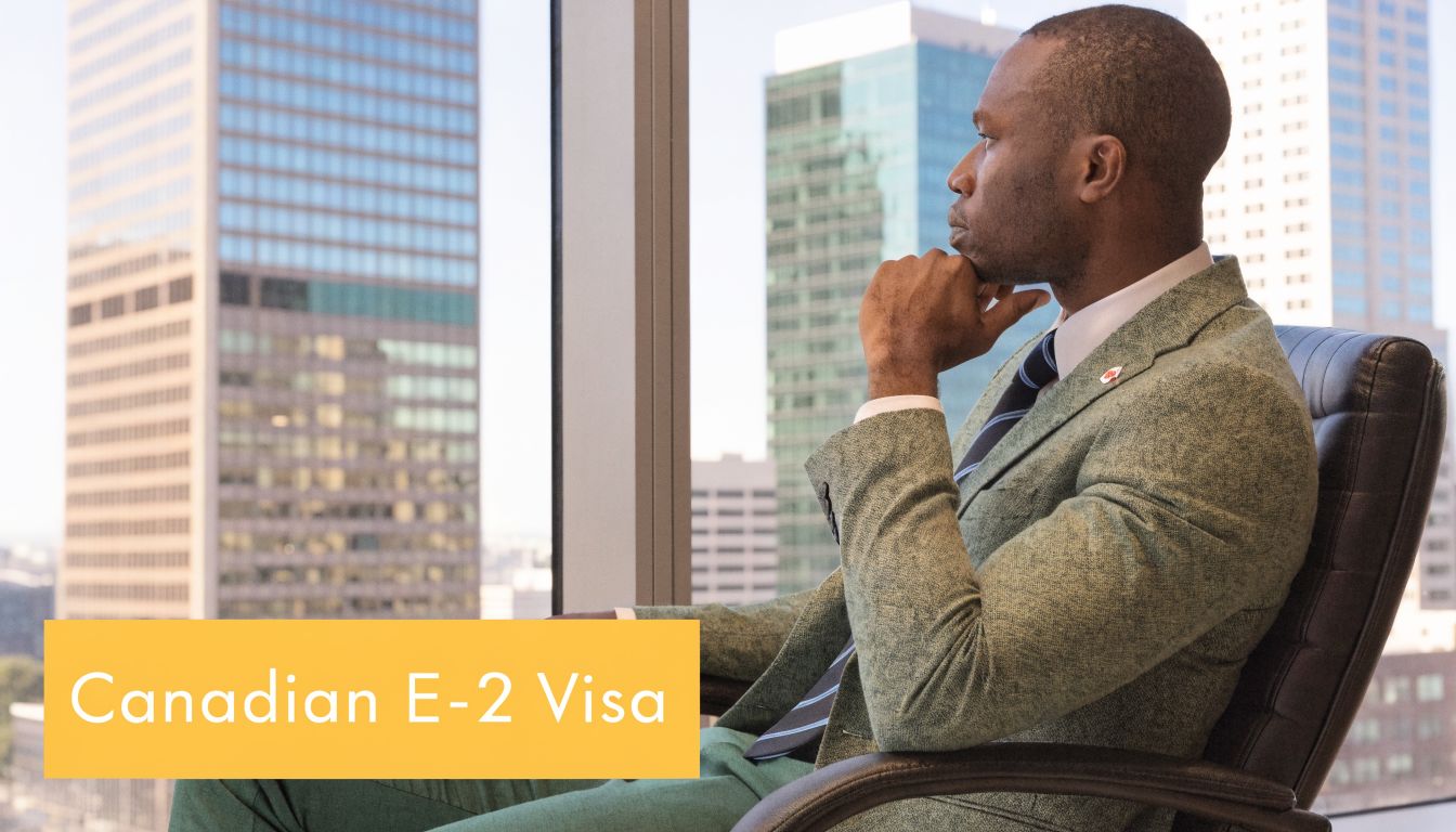 A professional man in a suit looking out of an office window at city buildings.