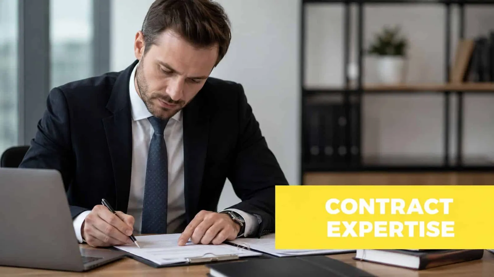 A professional man in a business suit reviewing and signing important documents at his office desk.